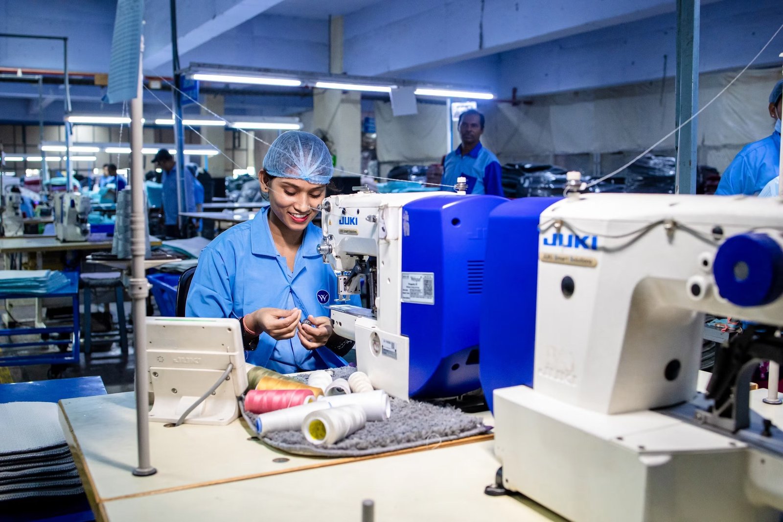 Seamstress operating an industrial sewing machine on the production floor